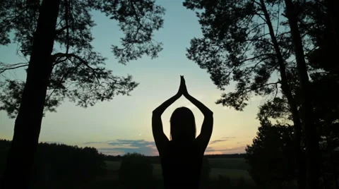 Happy young woman silhouette against sky lifts hands up in air Stock Footage