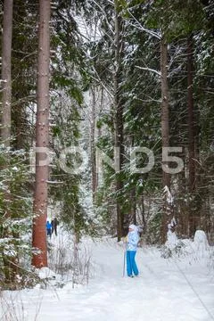 Happy young woman standing on ski in deep winter forest Stock Photos
