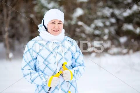 Happy young woman standing with ski poles in deep winter forest Stock Photos