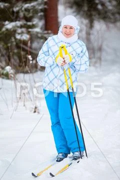 Happy young woman standing on ski with poles in hands Stock Photos