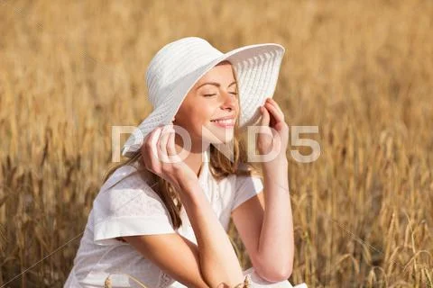 Happy young woman in sun hat on cereal field Stock Photos