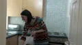 Happy young woman sweeping kitchen floor HD Footage