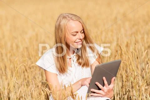 Happy young woman with tablet pc on cereal field Stock Photos