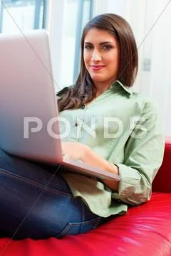 Happy Young Woman Using Laptop On Sofa