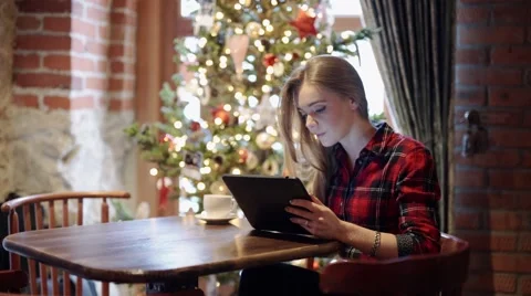 Happy young woman using tablet pc in front of christmas tree Stock Footage 58190751