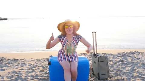 Happy young woman on vacation with a suitcase showing thumbs up Stock Footage