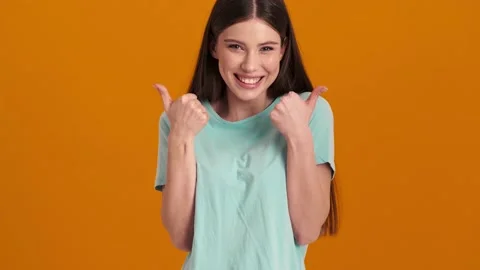 A happy young woman wearing basic T-shirt is doing thumb-up gesture Video stock 154316520