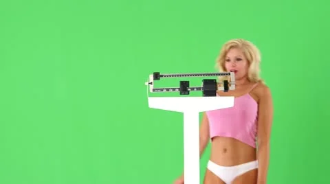 Happy young woman weighing self on scales Stock Footage