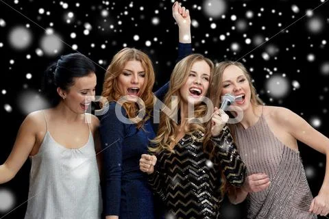 Happy young women with microphone singing karaoke Stock Photos