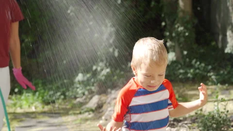 Hapy Boy Laughs and Plays Under Garden Water Spray in Sunny Crimea Stock Footage 312089118