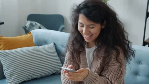 Hapy girl using smartphone touching screen then smiling getting good news Stock Footage 142043785