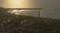 Harbor by coast town with boats separated from sea by breakwater in sunset glow HD Footage