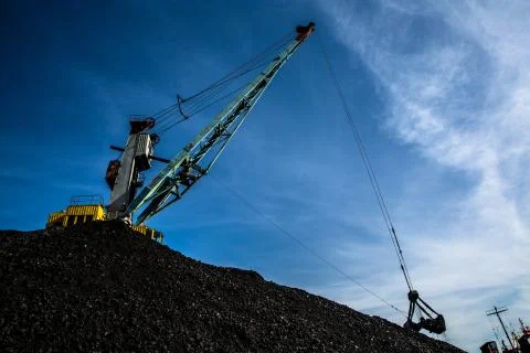 Harbor crane loading coal against a blue sky and clouds Stock Photos