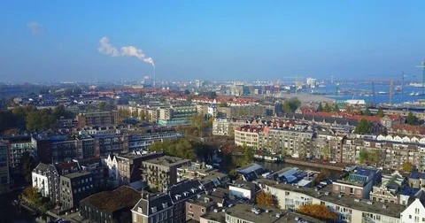 Harbor cranes and a steam plume beyond old brick rooftops Vídeo Stock 71294446