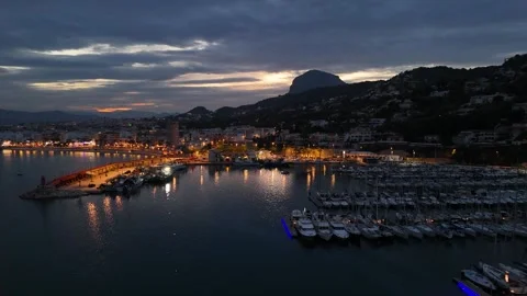 Harbor at dusk with Penon de Ifach and illuminated Mediterranean waterfront 動画素材 337166437