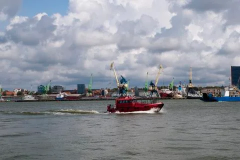Harbor traffic passing loading docks with cranes on a stormy day Stock Photos