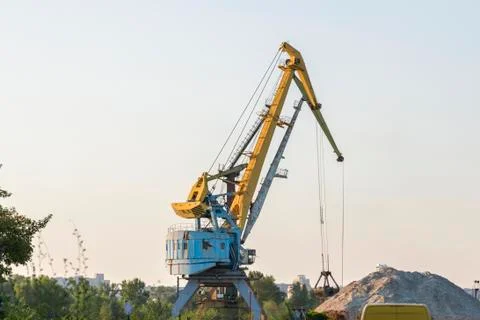 Harbour cranes are loading sand and gravel on a barge. Loading materials by c Stock Photos