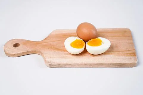 A hard-boiled chicken egg cut in half at the front, with a whole chicken eg.. Stock Photos