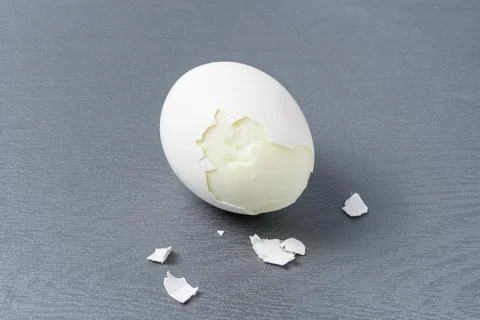 Hard boiled egg with broken shells on a gray cutting board Stock Photos