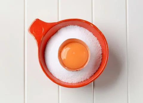 Hard-boiled egg in red measuring cup with salt Stock Photos