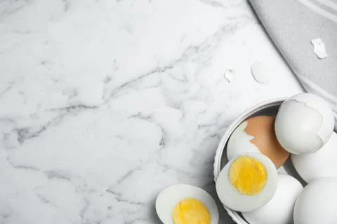 Hard boiled eggs and kitchen towel on white marble table, flat lay. Space for Stock Photos