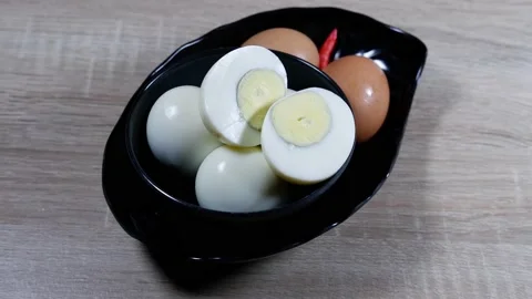 Hard boiled eggs in a black bow;, sliced in halves on wooden background Stock Footage 235615822