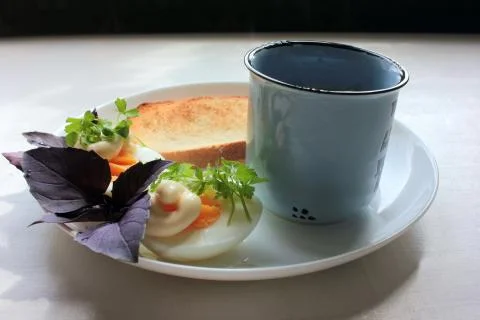 Hard boiled eggs cut in half, parsley, basil, crispy white toast and coffee Stock Photos