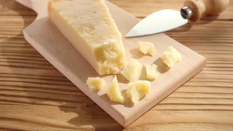 Hard cheese with a knife on a cutting board. Wooden background. Close-up Stock Footage 244369159