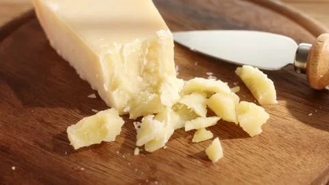 Hard cheese with a knife on a cutting board. Wooden background. Close-up Stock Footage 244449537
