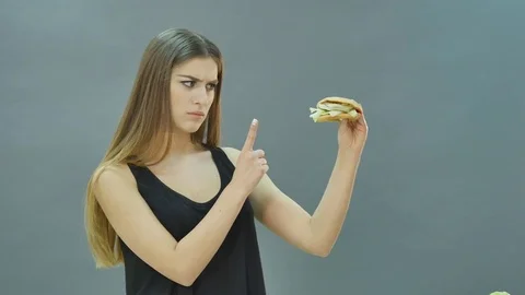 Hard choice: apple or burger, flustered girl decided to go on a diet Stock Footage 70868433