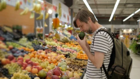 Hard choosing between red and green apples in grocery market. Young caucasian Stock Footage 97855500