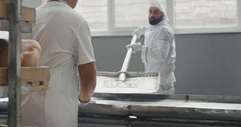 Hard day working process of unloaded the bread from oven machine on the special Stock Footage 112438885