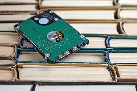 Hard drive on a stack of old shabby paper books. Comparison of storage media Stock Photos