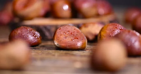 A hard edible chestnut fruit in a brown shell covered with water droplets on a Stock Footage 320816279