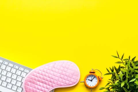 Hard exhausing work. Sleep mask on yellow office desk top-down copy space Foto stock