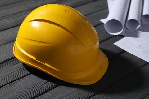 Hard hat and different engineering drawings on grey wooden table, closeup Stock Photos