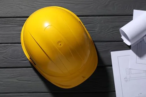 Hard hat and different engineering drawings on grey wooden table, flat lay Stock Photos