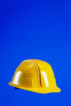 Hard hat for Labour Day concept. Yellow helmet isolated on blue vertical ba.. Illustrazione stock