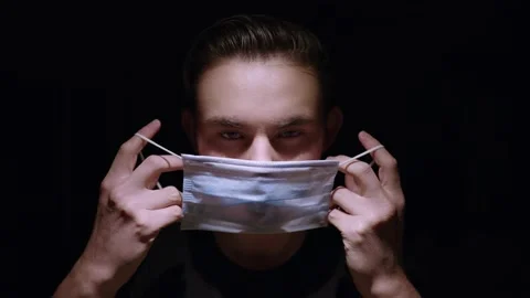 Hard lit overhead light on pale caucasian male putting on medical mask Stock Footage 143068992