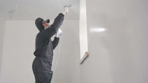 Hard manual labor at a construction site. Painter builder worker paints with an Stock Footage 239814688
