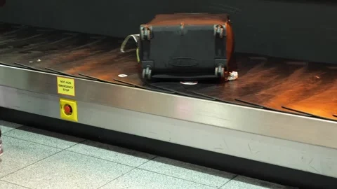 Hard-shell suitcase sitting on a moving baggage carousel at Dusseldorf Airport Stock Footage 329065738