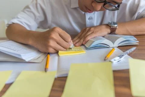 Hard studying student using eraser and doing homework on wooden desk Stock Photos