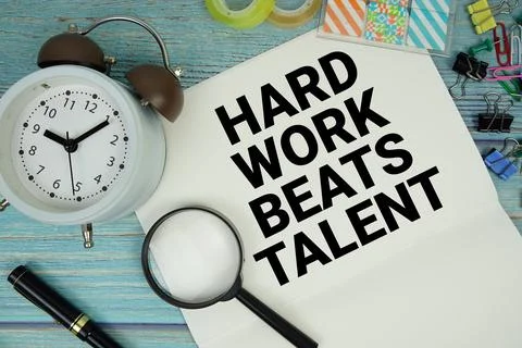 Hard Work Beats Talent text on a paper surrounded by office supplies, a mag.. Foto stock