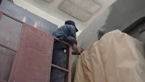 Hard work at the depot. A worker in overalls and a respirator polishes the Stock Footage 196357531