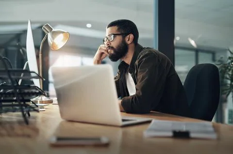 Hard work gets it all. a young businessman using a computer during a late night Stock Photos