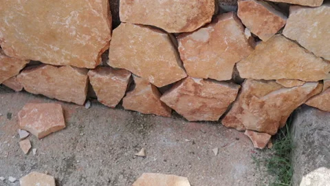 Hard work with laying decorative orange stone wall on construction site Stock Footage 164596661