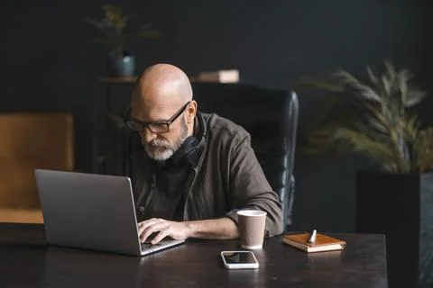 Hard worker concept, dedicated mid-aged man spends day immersed in work Stock Photos