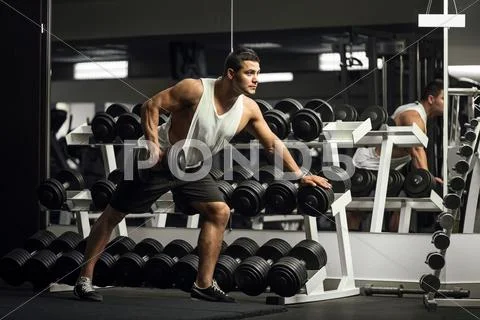 Hard working athletic man training with a dumbbell Stock Photos