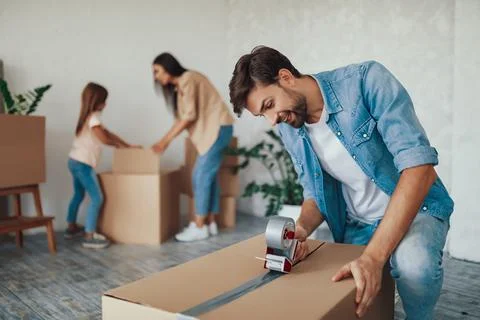 Hard-working father taping up boxes with stuff to move out Stock Photos