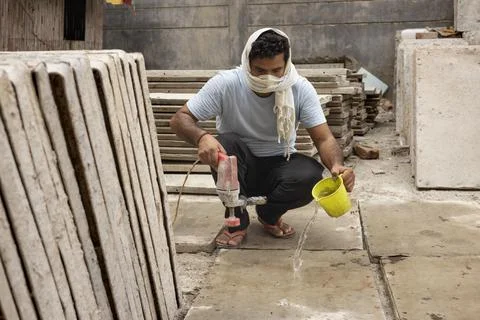 A HARD WORKING LABOURER USING ELECTRIC EQUIPMENT ON TILES Stock Photos